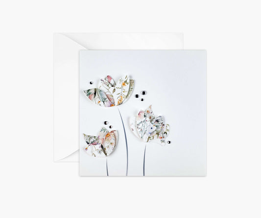 3 flowers die cut from floral patterned paper and layered. Silver gemstones highlighting