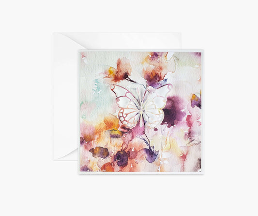 Abstract watercolor background in shades of cyan, yellow and reds with a butterfly die cut in the center.