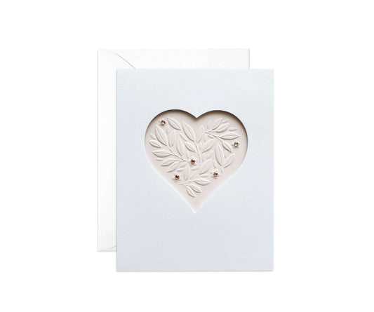 Die cut heart with embossed leaves on a pale pink paper with pink gemstones