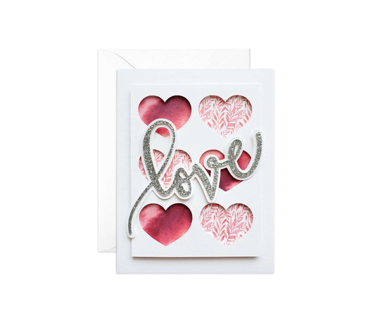 Die cut Valentine's Day card with the word "love" in silver glitter with 6 hearts cut out of white card stock