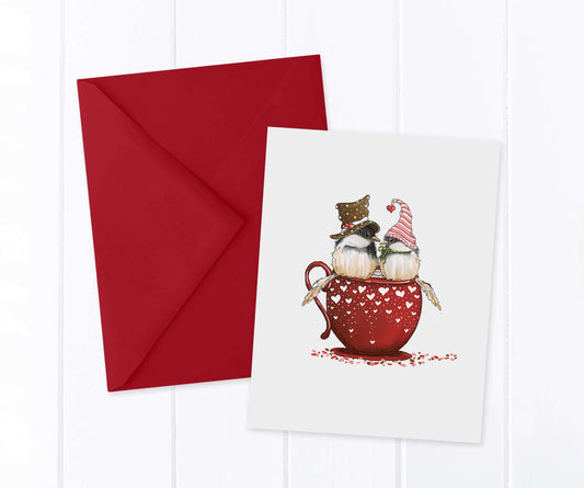 2 festive chickadees sitting on the rim of a red heart teacup