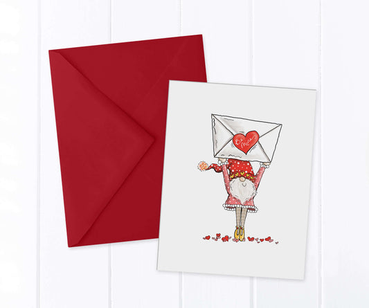 A festive gnome holding an oversized valentine over his head that says "be mine"